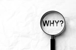 Why with question mark inside magnifying glass on paper background. Concept of business analysis, asking questions, researching information with copy space. photo