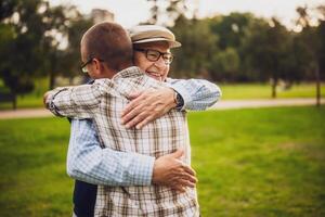Happy grandfather and grandson are hugging and embracing in park. photo