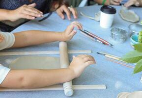 a child rolls natural-colored clay at a master class.children's creativity outside with adult photo