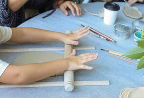 a child rolls natural-colored clay at a master class.children's creativity outside with adult photo