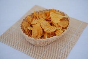 Crispy potato chips in a basket on white background. photo