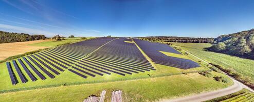 Panoramic image of a large solar field on a green meadow in daylight photo