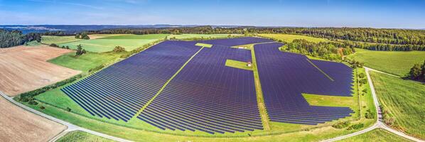 Panoramic image of a large solar field on a green meadow in daylight photo
