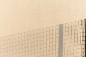 Shadow of fence creating geometric pattern on wall photo