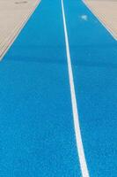 Running track texture with white stripe dividing the blue surface photo
