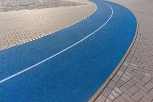 Blue running track curve surrounded by paving stones photo