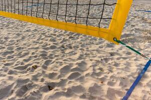 Empty beach volleyball court with yellow net on sand on sunny day photo