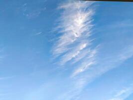 A clear blue sky with fluffy white clouds drifting lazily during a sunny afternoon in a serene outdoor setting photo