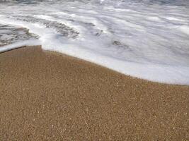 A serene beach at midday with gentle waves lapping the shore and clear blue skies inviting relaxation photo