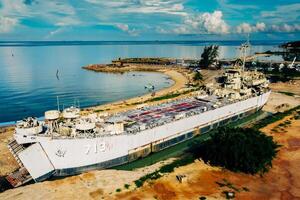Abandoned Military Ship on Sandy Beach with Clear Blue Sky and Calm Ocean in Background photo