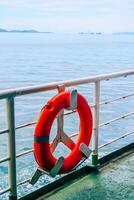 Bright Orange Lifebuoy on Ferry Deck with Ocean and Distant Islands in Background on a Clear Day photo