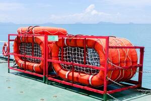 Bright Orange Life Rafts on a Ship Deck Overlooking a Calm Ocean with Distant Islands Under a Clear Blue Sky photo