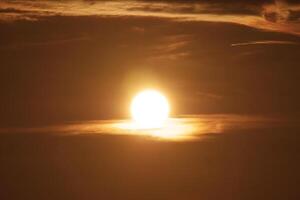 Stunning Sunset with Golden Sun and Dramatic Clouds Creating a Warm and Serene Atmosphere in the Evening Sky photo