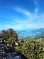 Vertical view of the Bay of Kotor and surrounding mountains in Montenegro, with a clear blue sky and copy space. Perfect for travel advertising, nature brochures, or social media backgrounds. photo