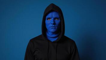Bluemasked veiled individual with hood on blue studio backdrop photo