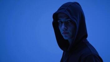 Hooded figure against blue backdrop photo