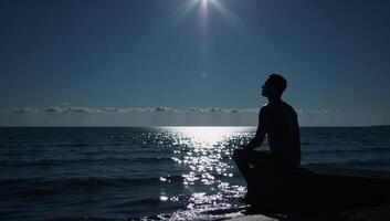 Lone figure contemplates under moonlit sky by waters edge photo