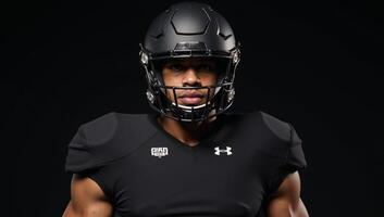 The image depicts a football player wearing allblack gear uniform helmet and face mask photo