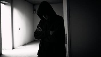 A hooded criminal or hacker is depicted with a dark silhouette in an ominous and faceless portrayal photo