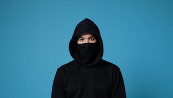 Hooded figure against blue backdrop photo