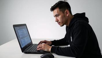 Hacker on his laptop poised for illegal digital intrusion cybercrime photo
