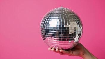 Hand with disco ball against pink backdrop fun retro theme perfect for parties photo