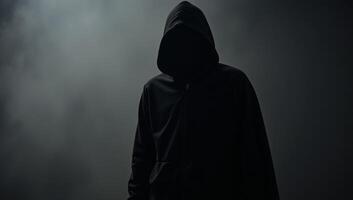 Hooded figure with gun in dark silhouette photo