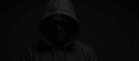Computer Hacker Blackhooded figure in Dark Moody Background photo