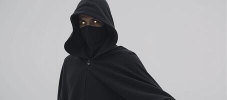 Hooded figure with glowing eyes silhouetted against a dark backdrop photo