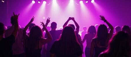 Vibrant nightlife dancing crowd in a purplishpinklit club scene with youthful energy and movement on the dancefloor photo