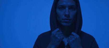 Hooded figure against blue backdrop photo