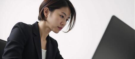 Asian woman in business attire holding a laptop at work photo