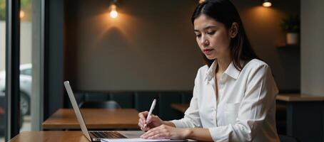Businesswoman deep in thought with laptop notebook at a busy coffee shop photo