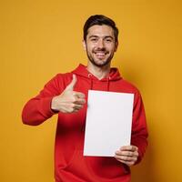 Man in red hoodie holds paper with thumbsup gesture photo