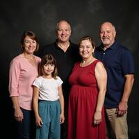 A genealogically themed group portrait showcases multiple generations standing together against a dark abstract backdrop remembering and honoring their ancestors created with photo