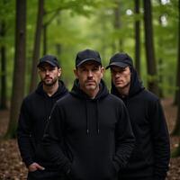 Three cloaked figures stand within a forest photo