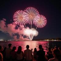 people observing summer fireworks over water at a festive gathering photo