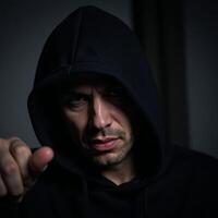 Criminal man with hooded appearance gazes at dangerous backdrop photo