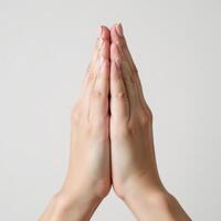Closeup image of female hands in prayer pose against a pure white background photo