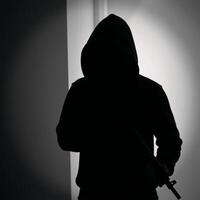 Silhouette of a hooded figure with a gun exuding mystery and danger photo