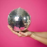 Hand with disco ball against pink backdrop fun retro theme perfect for parties photo