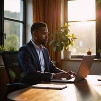 Mature Black financial advisor at home during golden hour typing with focused gaze while on a call in a stylishly decorated contemporary residence photo