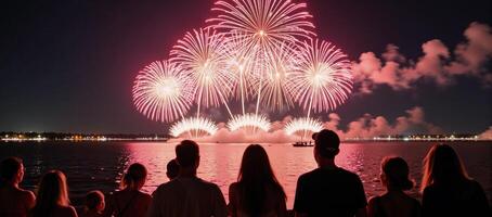 people observing summer fireworks over water at a festive gathering photo