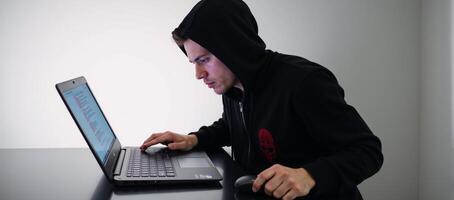 Hacker on his laptop poised for illegal digital intrusion cybercrime photo