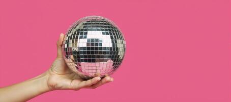 Hand with disco ball against pink backdrop fun retro theme perfect for parties photo