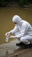 Research scientist collects contaminated riverwater sample using protective gear photo