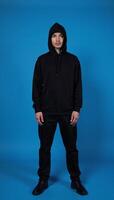 Hooded figure against blue backdrop photo