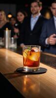 A cocktail glass filled with an alcoholic beverage sits on a bar table at a nightclub or restaurant photo
