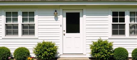 A white cottage with two windows and a front door photo