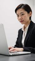 Asian woman in business attire holding a laptop at work photo
